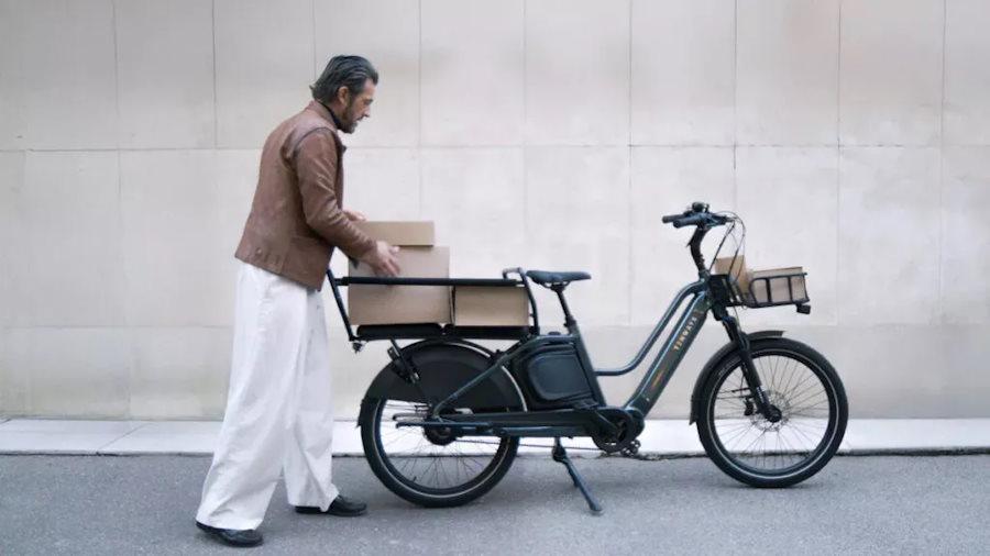 Un homme qui met des cartonsà l'arrière de son vélo électrique cargo